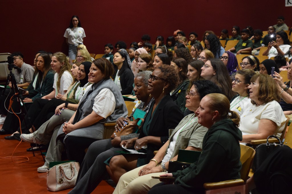 Audience members engaging and smiling during the 2025 Leadership Day assembly at P.S. 74, showcasing a diverse group of parents, students, and faculty.
